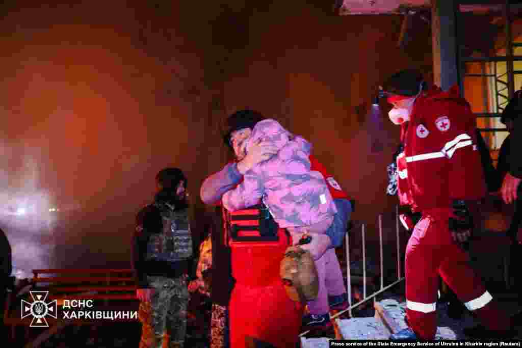 Мэдык выносіць дзіця з ахопленага агнём шматпавярховага будынку ў Харкаве пасьля расейскага абстрэлу
