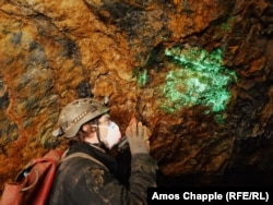 Cristale radioactive de autunit strălucesc sub lumina unei lanterne UV într-o mină de uraniu abandonată din sudul Boemiei.