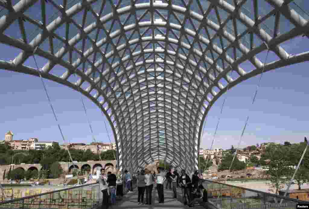 Pedestrians walk across the recently built Bridge of Peace, which traverses the Kura River in Tbilisi's old town.