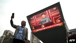 O femeie își face un selfie în fața unui ecran care îl arată pe liderul chinez Xi Jinping în timpul discursului susținut cu ocazia sărbătoririi a 100 de ani de existență a Partidului Comunist Chinez, 1 iulie 2021.