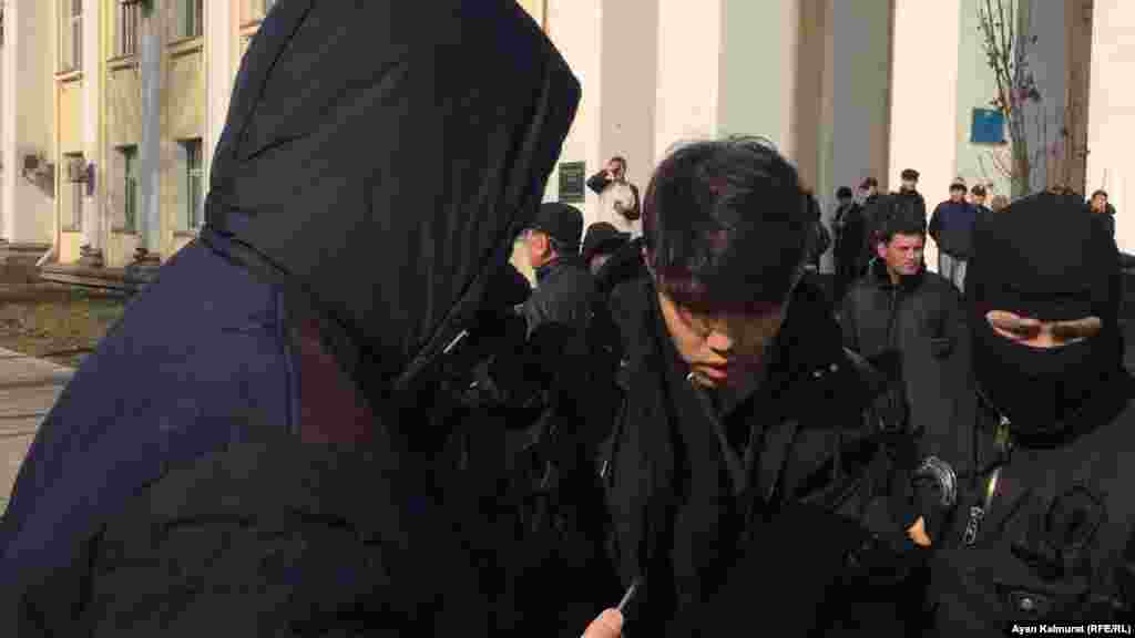 Арнайы жасақ сарбаздары "Нұр Отан" кеңсесі алдында тұрған жастардың бірін ұстап жатыр.