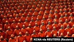 La paradă, personalul militar a mărsăluit în costume de protecție portocalii și măști anti-gaze. 