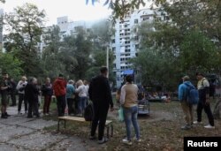 Banorët qëndrojnë pranë një ndërtese banimi të dëmtuar gjatë një sulmi me raketa ruse në Dnipro, Ukrainë, 20 shtator 2025.