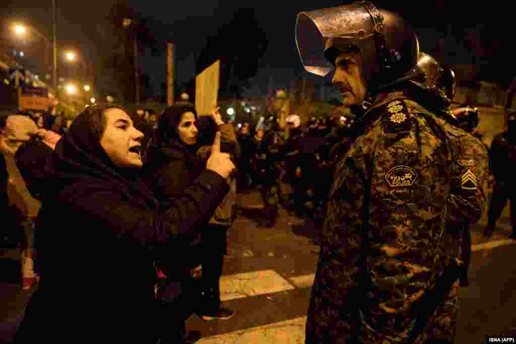 A woman attending a candlelight vigil for the victims of the Ukrainian airliner crash talks to a policeman on January 11 at Tehran's Amir Kabir University.