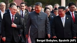 Орусиянын президенти Владимир Путин Кытайдын лидери Си Цзиньпиндин сол жагында, Түндүк Кореянын башчысы Ким Чен Ын сол капталында баратат.