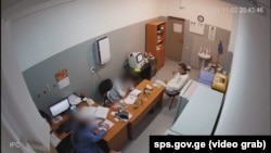 კადრი 5 ნოემბერს, იუსტიციის სამინისტროს პენიტენციური სამსახურის მიერ გავრცელებული ვიდეოდან, სადაც მიხეილ სააკაშვილი ასახულია რუსთავის პენიტენციური დაწესებულების სამედიცინო ოთახში 