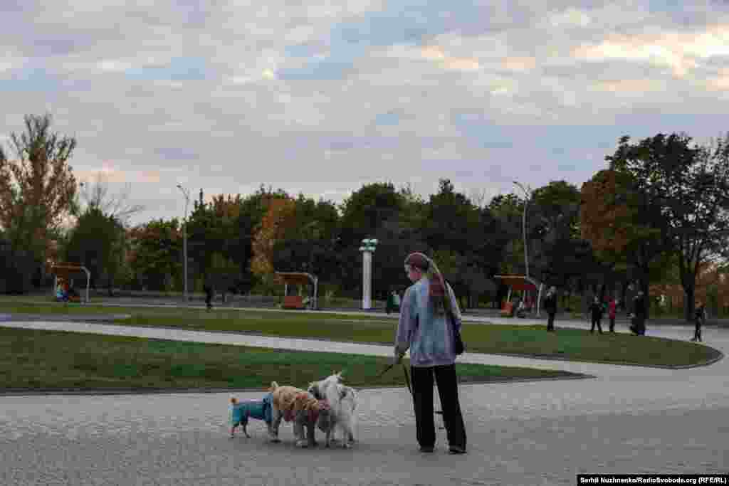 Дзяўчына гуляе з сабакам у Юбілейным парку, дзе стаіць тронец зь сьцягам Украіны, які расейскія войскі апошнім часам намагаюцца зьнішчыць FPV-дронамі