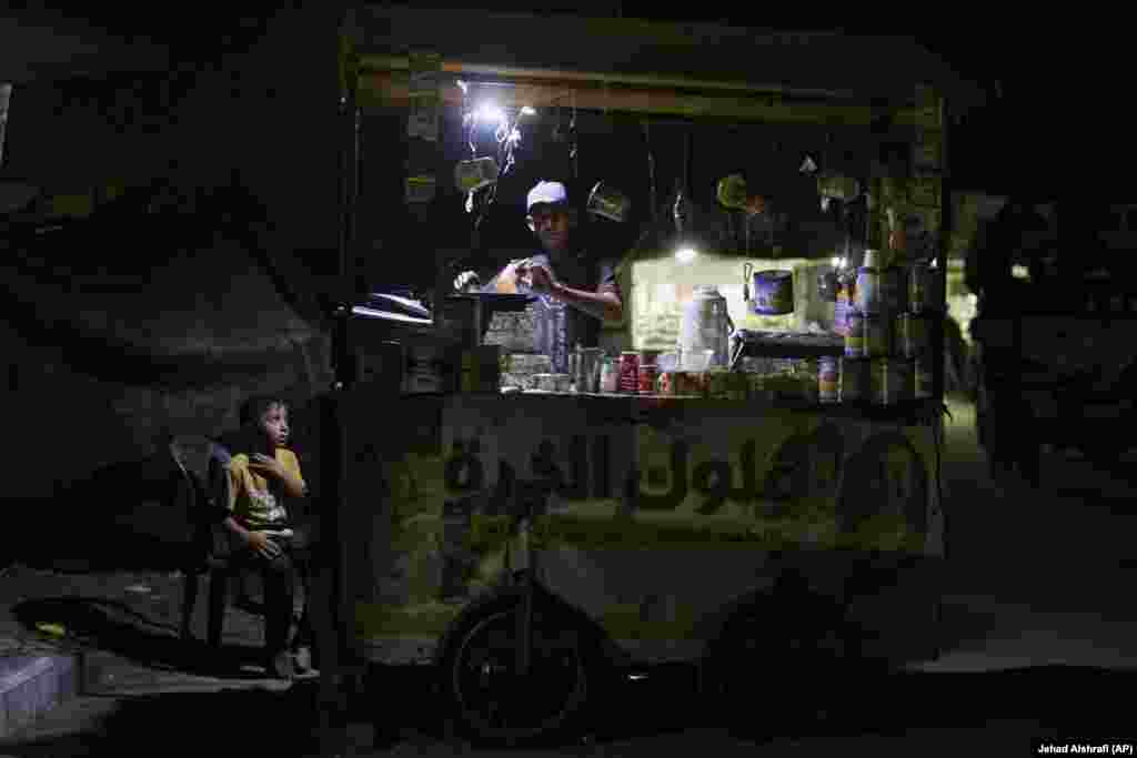 Një djalë palestinez duke shikuar një shitës ambulant teksa po piqte misër.