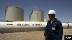 A worker stands next to an export pipeline at the Tawke oil refinery near the village of Zacho in Iraq's autonomous region of Kurdistan.