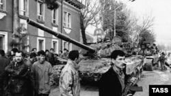 Сүрөттө: Тажикстандагы 1990-жылдардагы атуулдук согуштун бир учуру. Өзбек колбашчы, полковник Махмуд Худайбердиев жетектеген өкмөттүк жоокерлер Түндүк Тажикстандагы Турсунзаде шаарында көтөрүлүшчү Надыр Абдуллаевдин күчтөрүн шаар сыртына сүрдү.