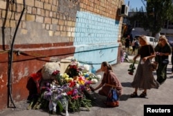 Жена поставя цветя на импровизиран мемориал в памет на жертвите на руската атака над Киев, 29 август 2025 г.