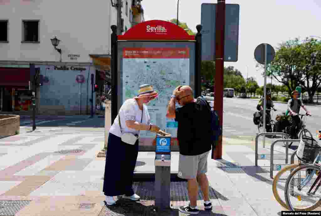 Par se rashlađuje vodom iz javne fontane u Sevilji, 29. juna.