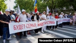O pancartă în rusă la Marșul familiei, organizat de PSRM, care se traduce: „Va exista familia, va exista și țara”. Chișinău, 15 iunie 2025