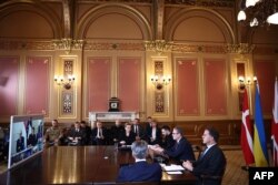 Premierul britanic Keir Starmer, președintele Ucrainei, Volodimir Zelenski, secretarul general al NATO, Mark Rutte, prim-ministrul danez, Mette Frederiksen și prim-ministrul olandez, Dick Schoof, în fața unui ecran, alături de alți participanți prin legătură video.