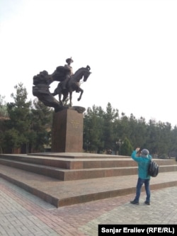Турист из Кыргызстана фотографирует статую Бабура в Андижане