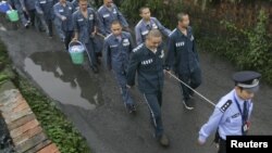 Укук коргоо кызматкери соттолуучуларды алып баратат. Кытай, 27-сентябрь, 2012-жыл