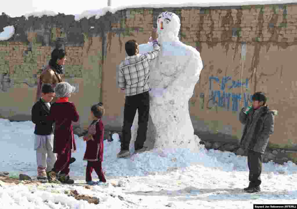 Афганистан. Взрослые с детьми лепят снеговика. 