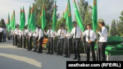 Baýdak göterip, çärä gatnaşýan oglanlar.