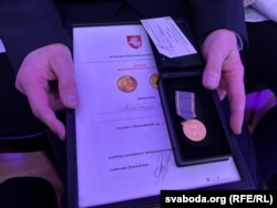 Пасьведчаньне пра ўзнагароду і сам мэдаль у руках Алеся Бяляцкага