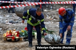 Punonjësit e emergjencës mbajnë një fragment të një rakete ruse Iskander-K që goditi një ndërtesë banimi në Kiev, më 1 gusht.