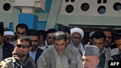 Afghan President Hamid Karzai (right) arrives in the village of Azizabad in the district of Shindand.