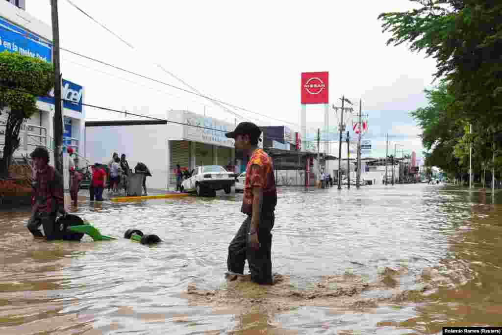 Люди пробираются по затопленной улице после проливных дождей, вызвавших разлив рек в Поза-Рика, штат Веракрус, Мексика, 10 октября 2025 года. REUTERS/Rolando Ramos