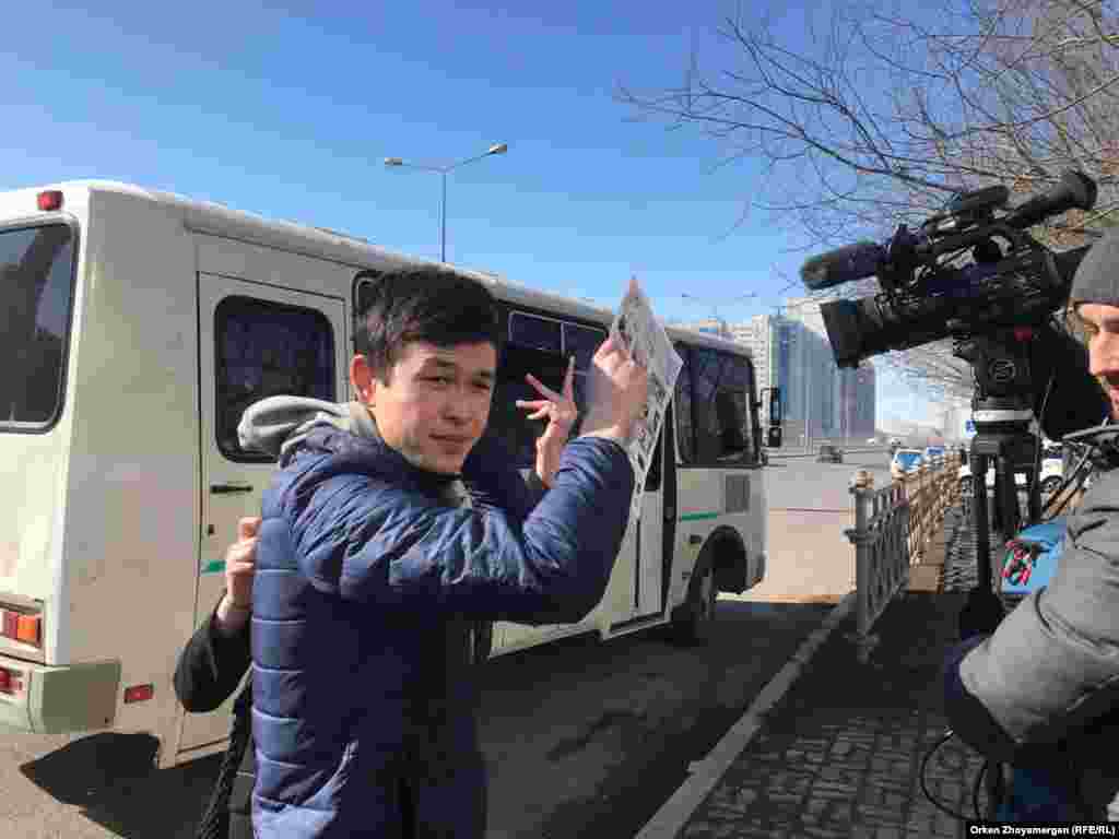 В Астане людей задерживали у торгового центра "Шапагат". Съемочную группу Азаттыка, журналистов Оркена Жоямергена и Тимура Айтмухамбетова, приехавших освещать происходящее, здесь встретила группа молодых людей, называвших себя "студентами". Они вмешивались в работу корреспондентов. Один из них пытался прикрыть объектив камеры листом бумаги, Астана, 22 марта 2019 года.&nbsp; &nbsp;
