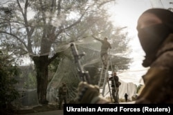 Военнослужащие 24-й механизированной бригады ВСУ устанавливают сетки против дронов над дорогой в прифронтовом городе Константиновка Донецкой области, 19 сентября 2025 года