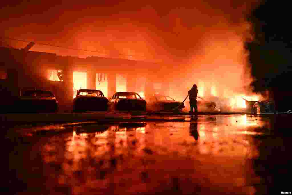 Украиналык өрт өчүрүүчү Запорожьедеги чакан ишканага орусиялык дрон тийгенден кийин кийин тутанган өрттү өчүрүүдө. 