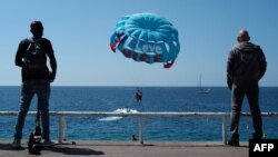 Снимката е илюстративна. Хора наблюдават лодка, теглеща "воден парашут" (парасейлинг) край Ница, Франция.