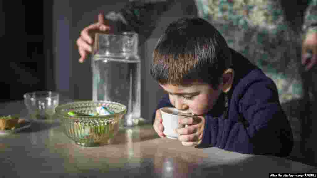 Сахір п'є воду на кухні