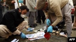 Pakistani security personnel collect evidence at the bomb blast site in Mardan on December 29. 